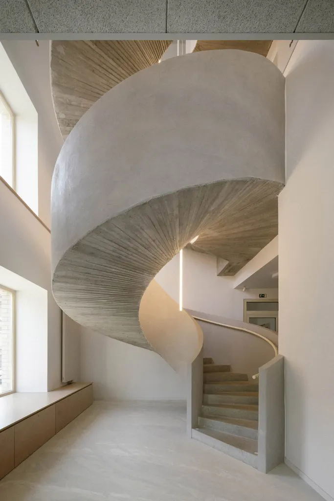 A spiral concrete staircase occupies the rounded corner of the building