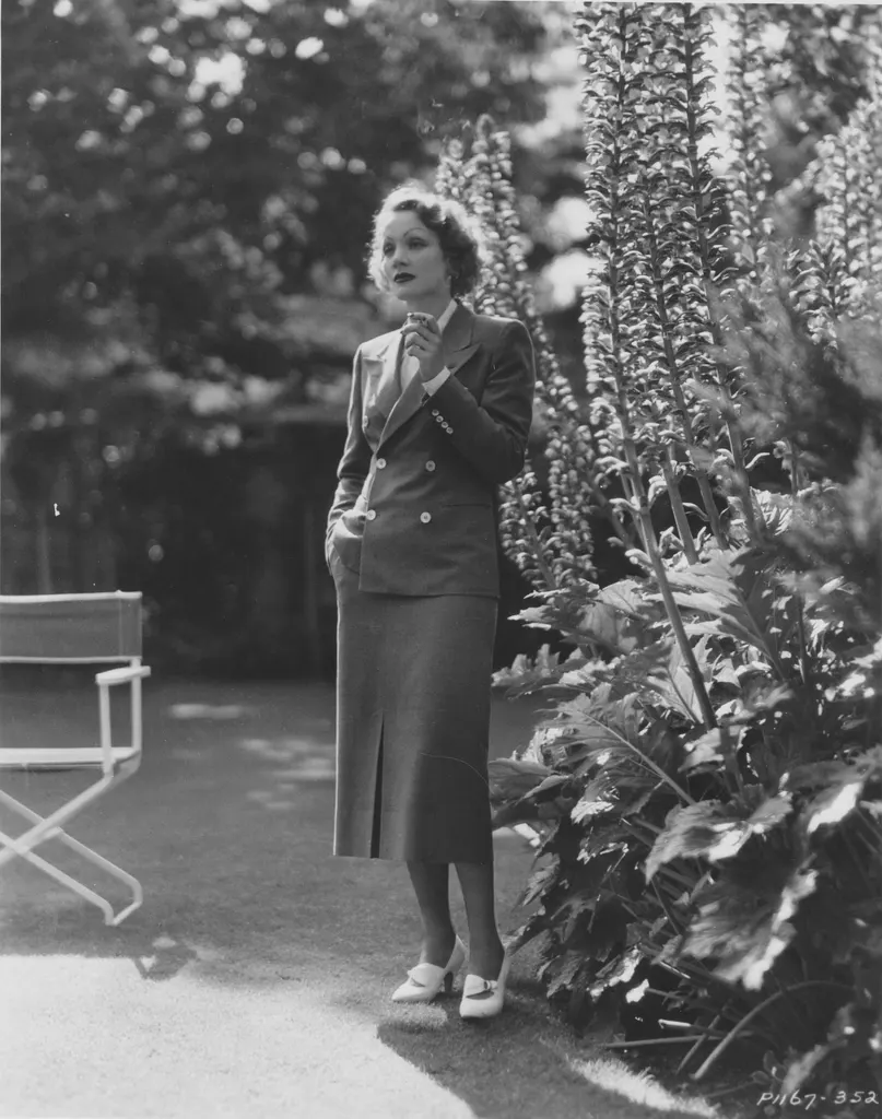 blackandwhite photo of Marlene Dietrich in her garden directors chair to left