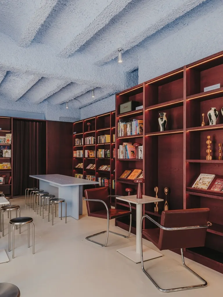 the burgundy shelving contrasts with the textured blue ceiling, creating the project’s distinctive material palette