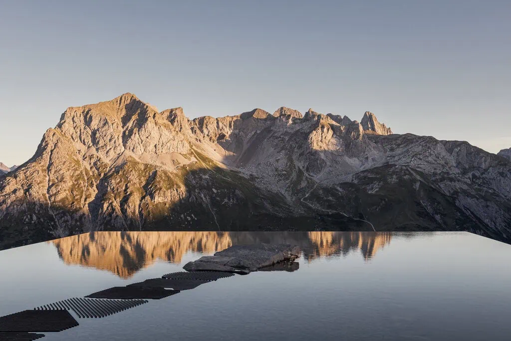 The pool of water reflects the Alpine surroundings