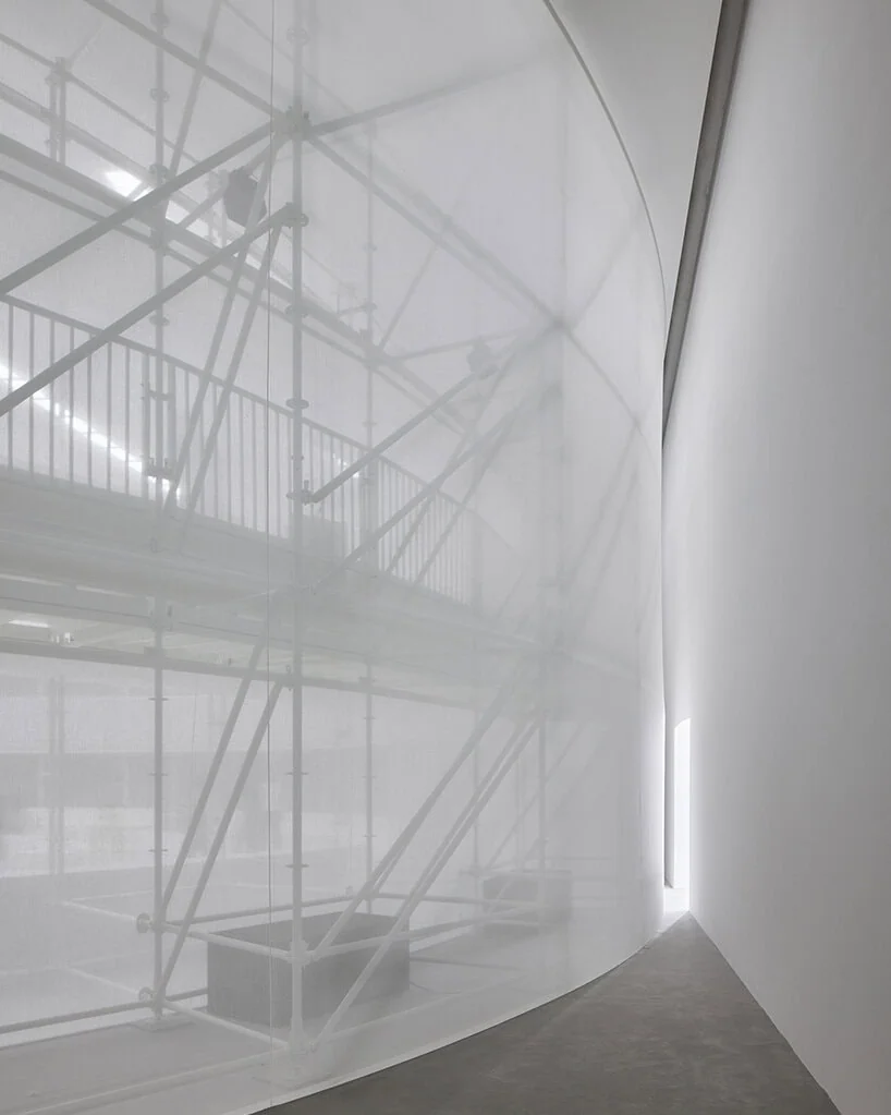 sheer white fabric wraps the exposed scaffold structure