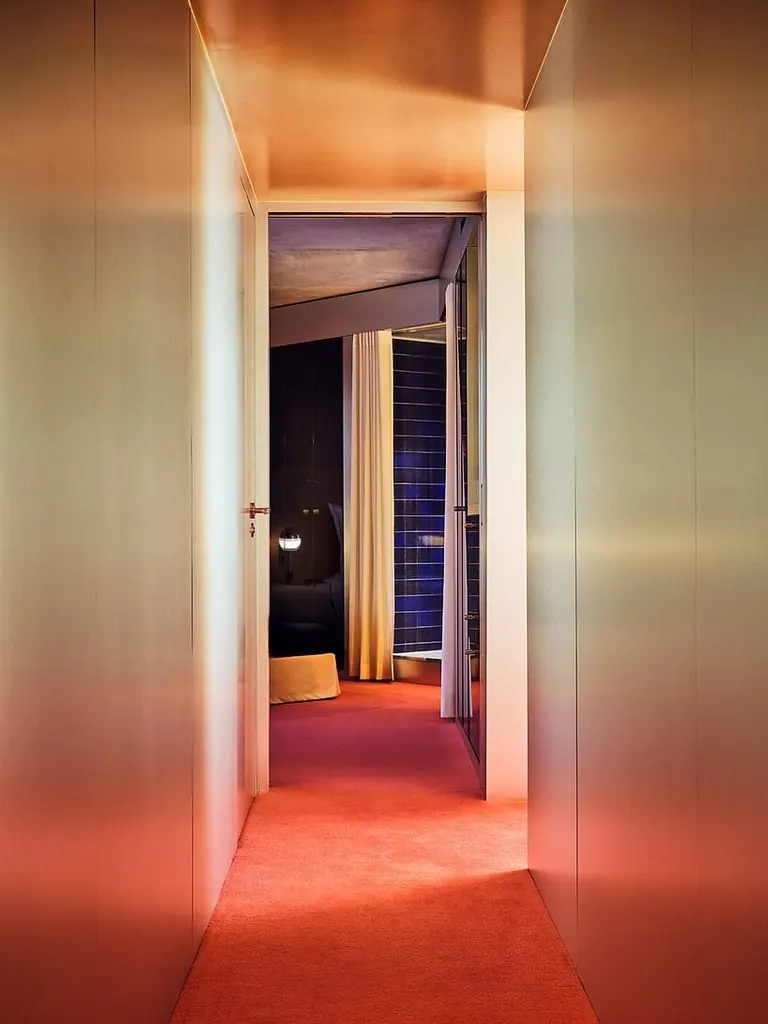 carpeted corridors extend the hotel’s soft, immersive interior language