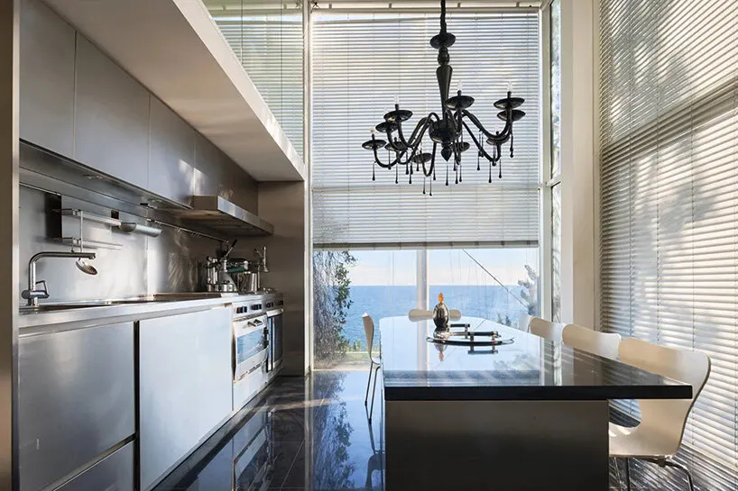 the kitchen and dining area combine stainless steel finishes with expansive glazing overlooking the water