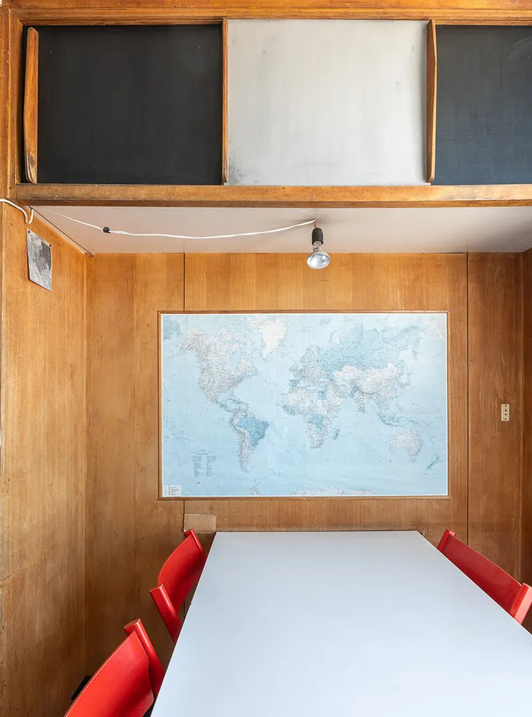 wood-paneled dining area with a large world map and red chairs