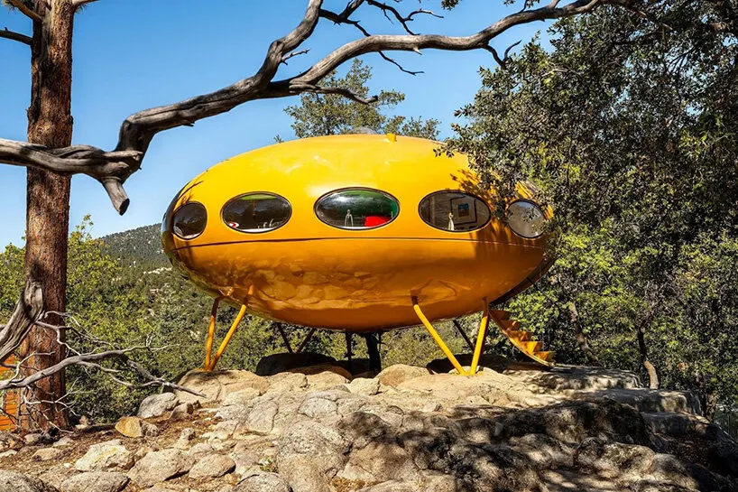 the yellow Futuro house stands on a rocky outcrop