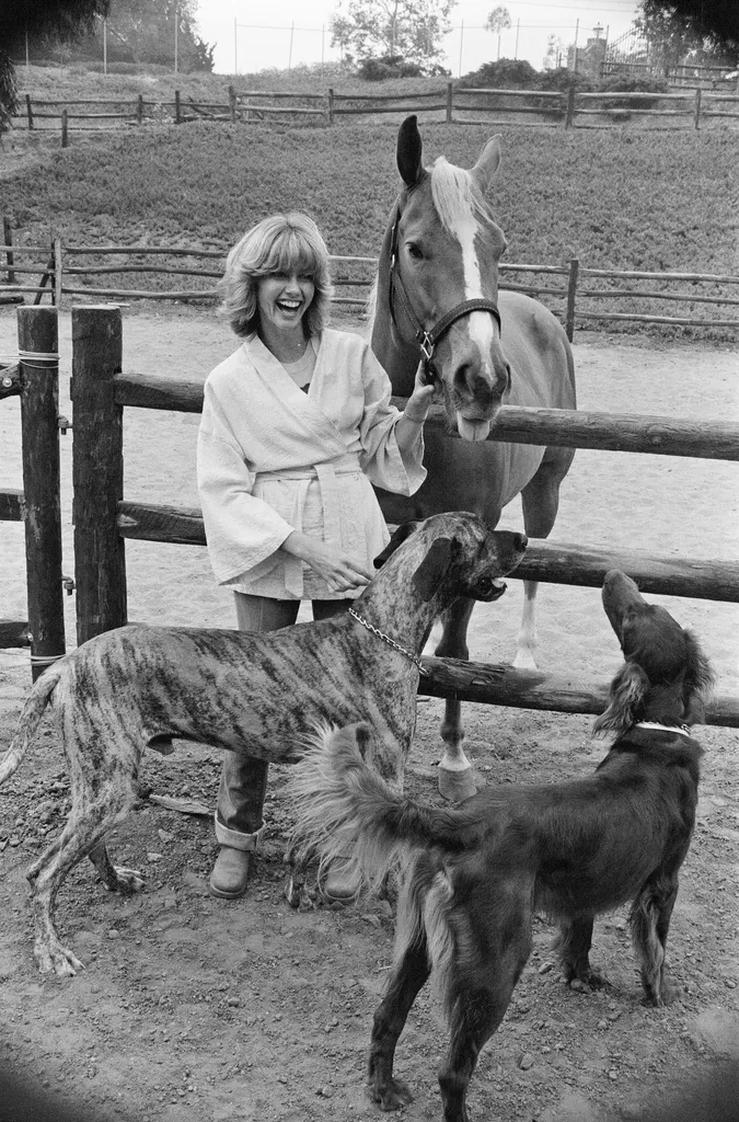 blackandwhite photo of Olivia NewtonJohn at home with horse two dogs