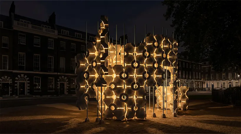 at night, warm illumination traces the pavilion’s curved geometry and transforms the structure into an intimate space