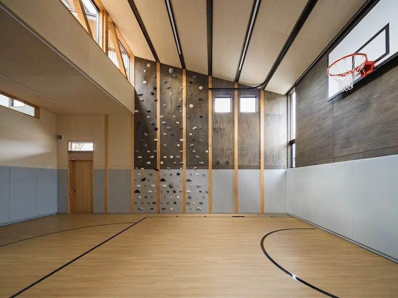 a flexible space with a basketball hoop and bouldering wall provides room for sports, play, and gatherings