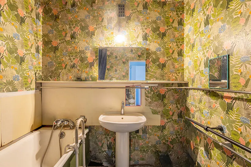the bathroom is lined with botanical wallpaper and fitted with a freestanding sink