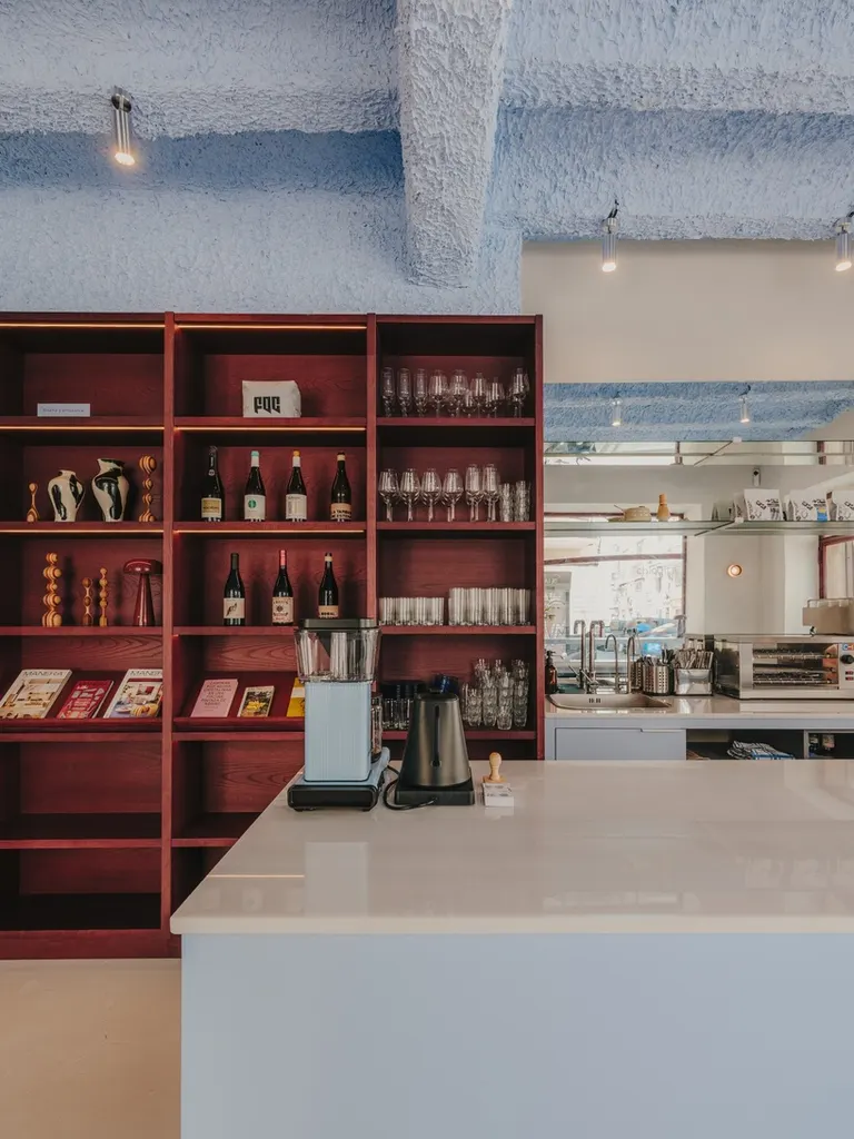 the wine bar and coffee counter are integrated into the continuous wooden shelving system